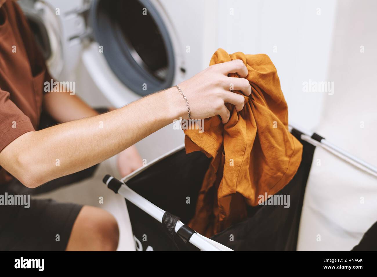 Young man loading washing machine with dirty clothes Stock Photo