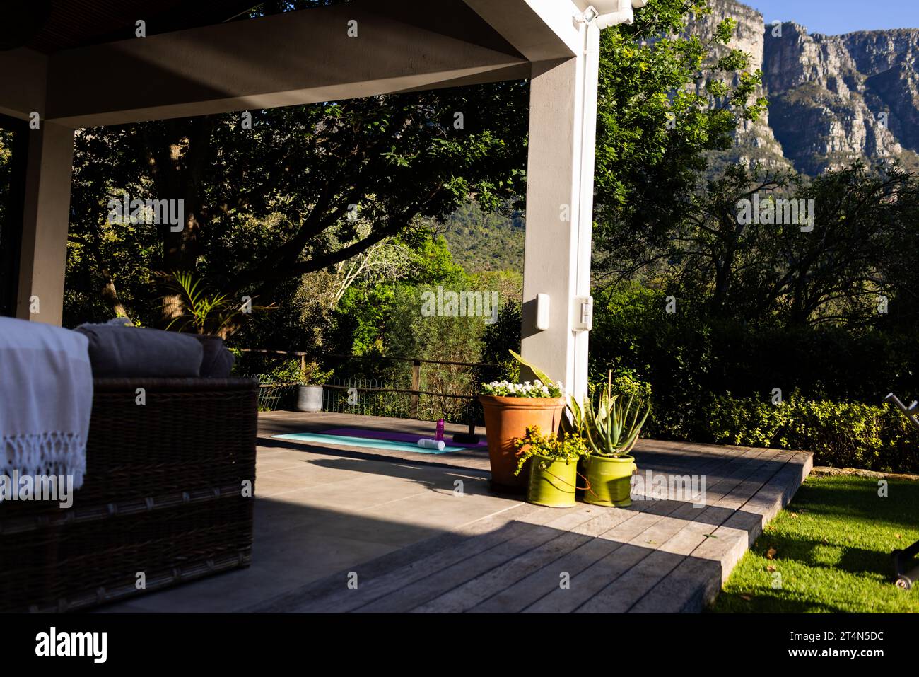 Outdoor furniture on terrace and yoga mat on deck in sunny garden, copy