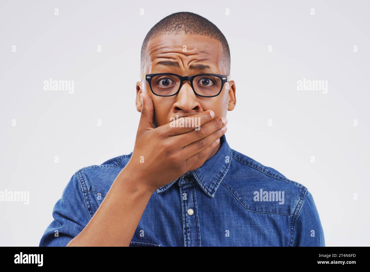 No...you must be mistaken. Studio shot of a young man looking shocked against a grey background. Stock Photo