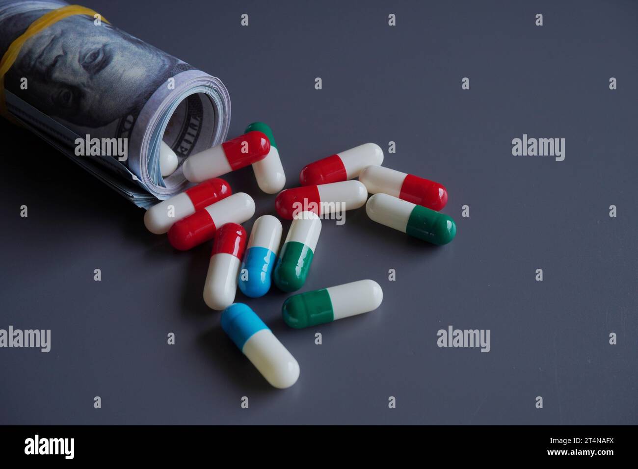 Money rolled up with medicine pills flowing out isolated on black background. Pharmaceutical industry profit, medical expenses concept. Stock Photo
