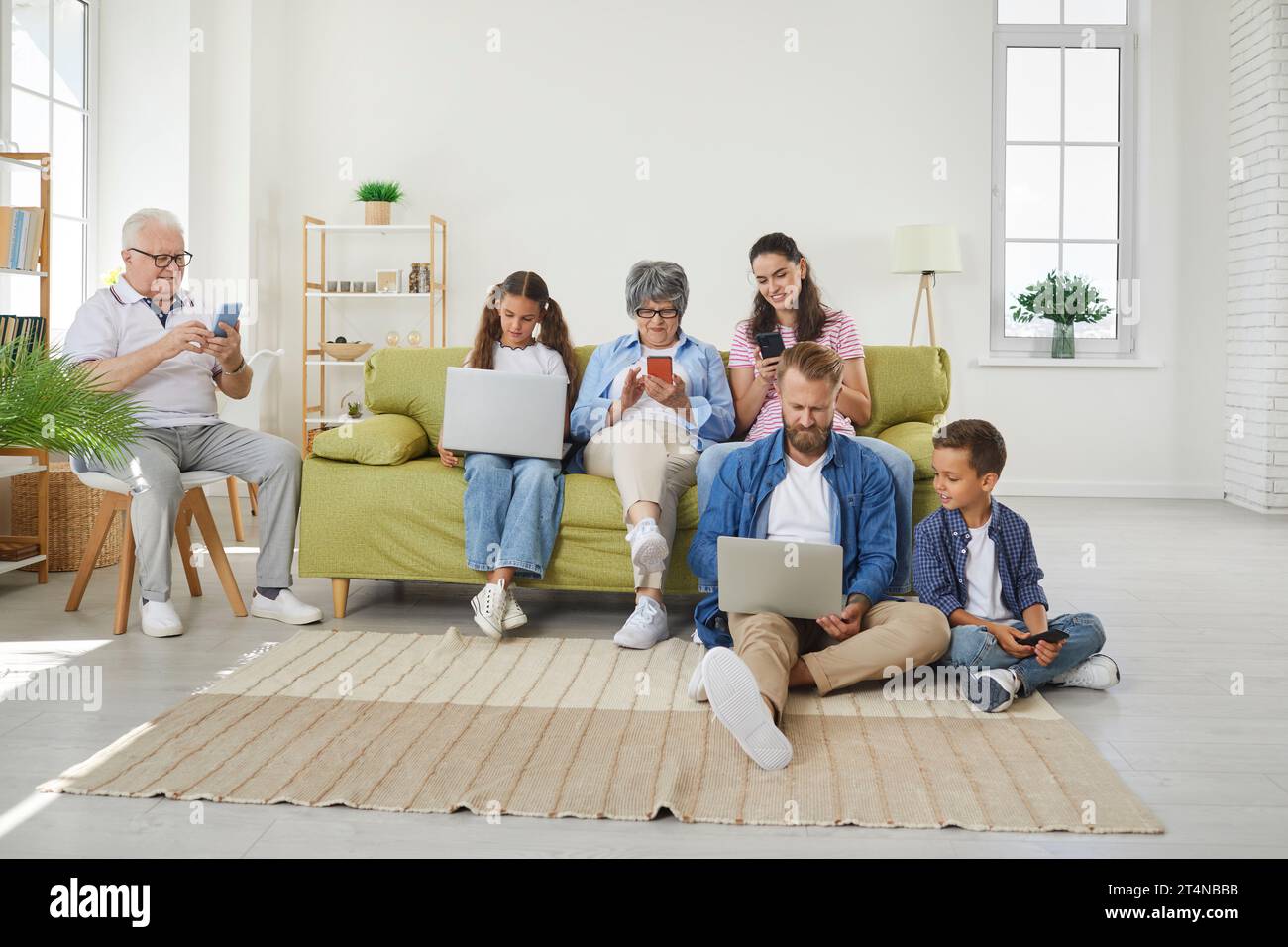 Big family using different electronic devices while sitting on sofa at home Stock Photo