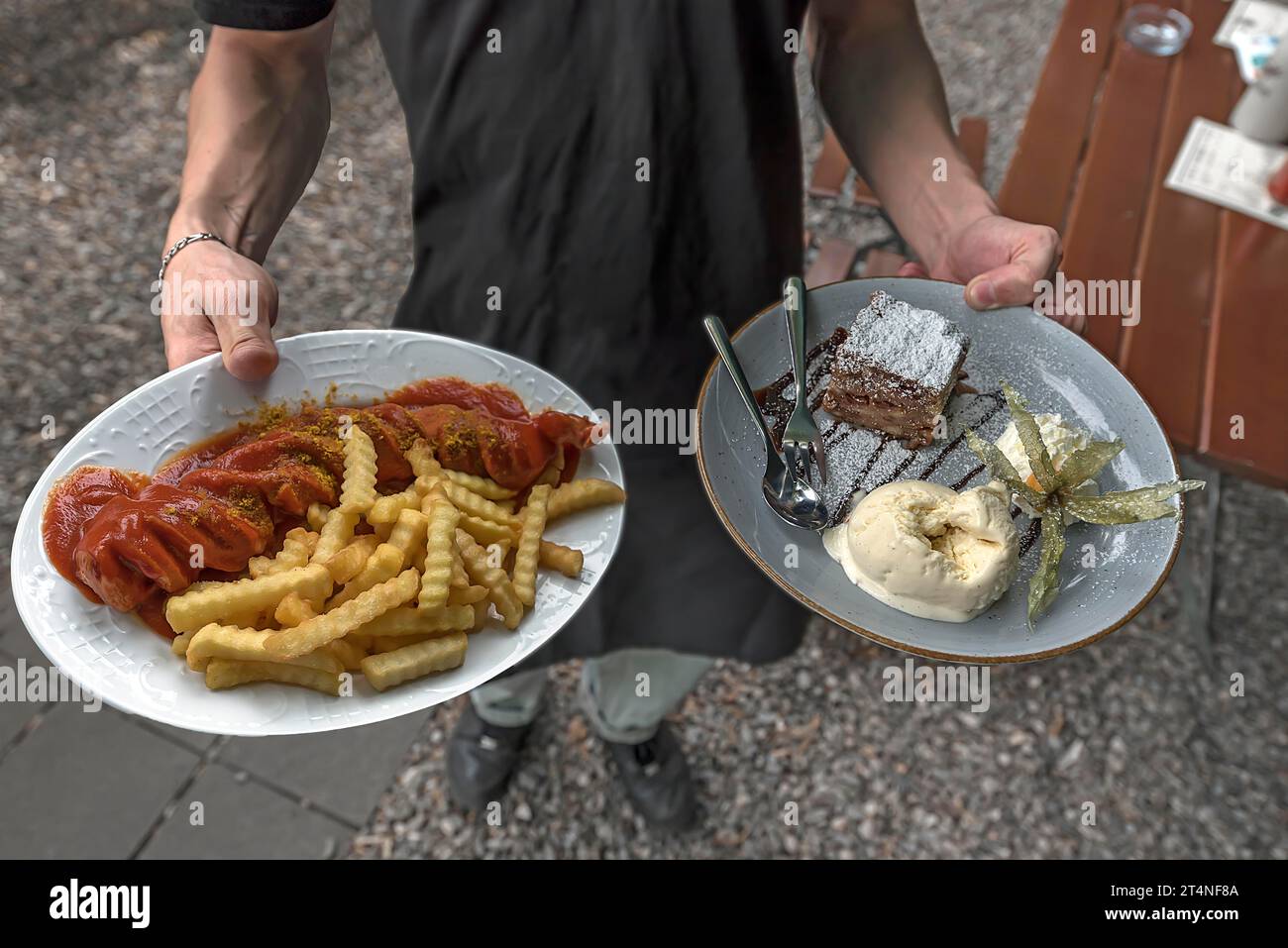 A waiter serves currywurst with fries and apple strudel with ice cream in a garden restaurant, Erlangen, Middle Franconia, Bavaria, Germany Stock Photo