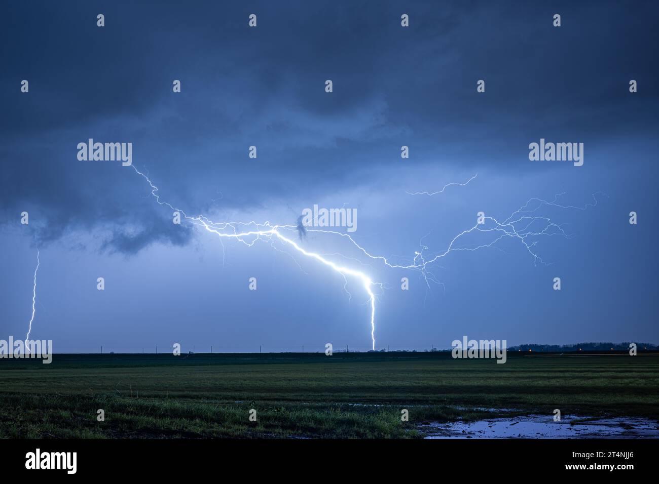 Exceptionally bright lightning strikes earth during a severe thunderstorm at night Stock Photo