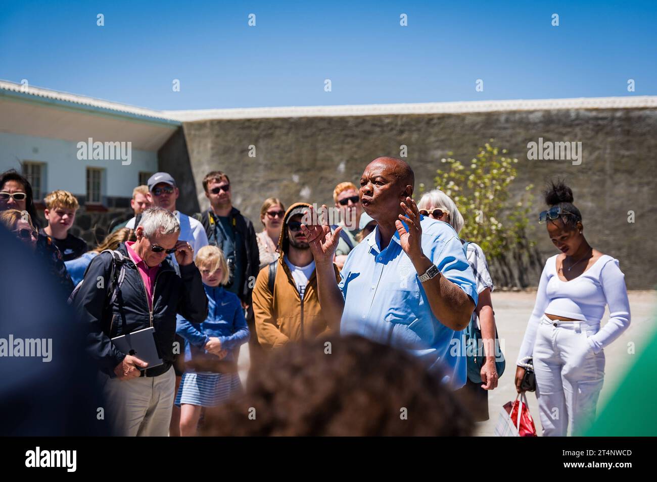 29.10.2023, xovx, Politik, Reise. Robben Island - Gefängnisinsel vor Kapstadt Führung einer Besuchergruppe durch Nelson Mandelas im Gefängnishof des Zellenblocks des Hochsicherheitstrakts auf der Gefängnisinsel Robben Island vor der Küste von Kapstadt, durch einen ehemaligen politischen Gefangenen, der der in diesem Gefängnis über viele Jahre inhaftiert wurde. In diesem Teil des Hochsicherheitstrakts verbrachte Nelson Mandela über 18 Jahre seiner Gefangenschaft in Einzelhaft. Der spätere Präsident Südafrikas Nelson Mandela verbrachte hier von 1964 bis 1982 seiner insgesamt 27-jährigen Gefangen Stock Photo