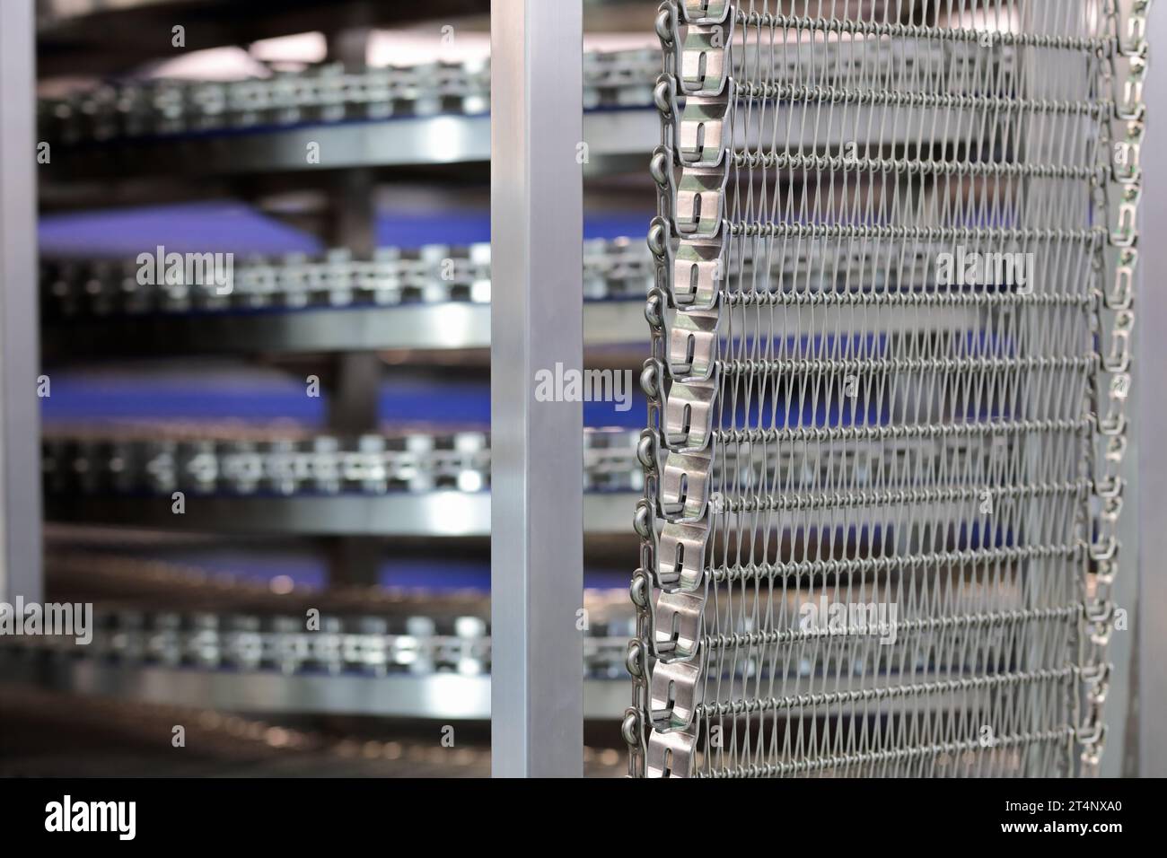 Spiral cooler for bread cooling in large bakery. Industrial spiral cooling tower conveyor machine. Selective focus. Stock Photo