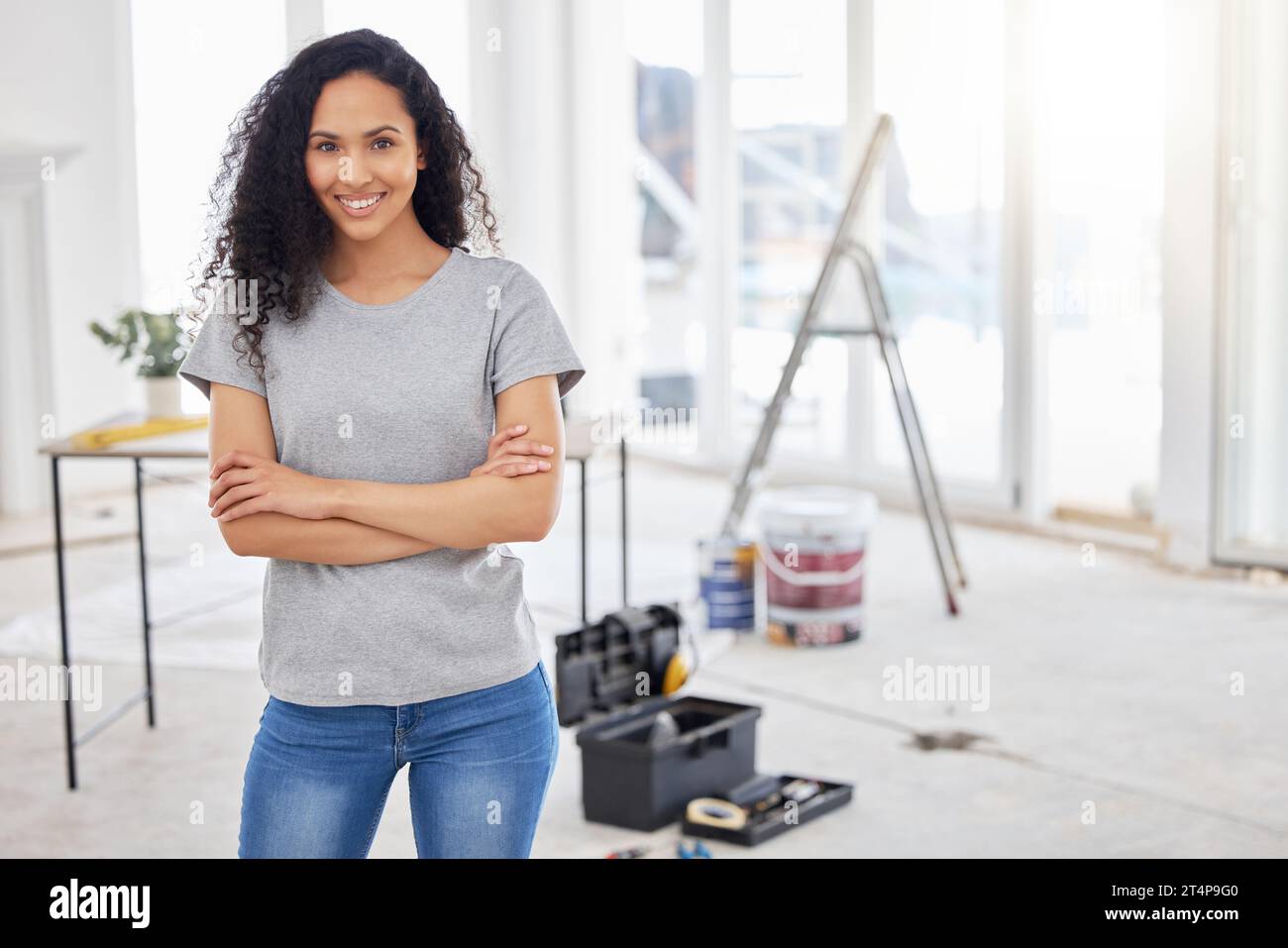 This room will look a little different in a bit. a woman standing in a room under renovations. Stock Photo
