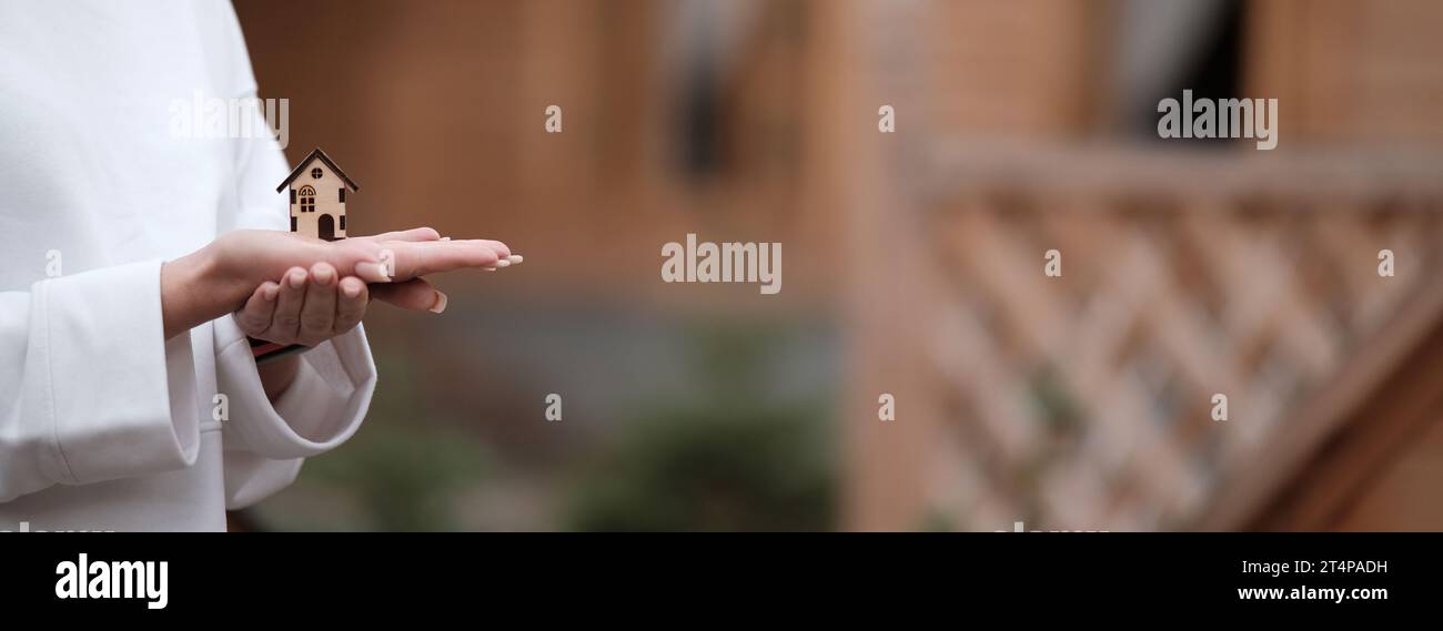 A small wooden house on a woman s hand against the background of a ...