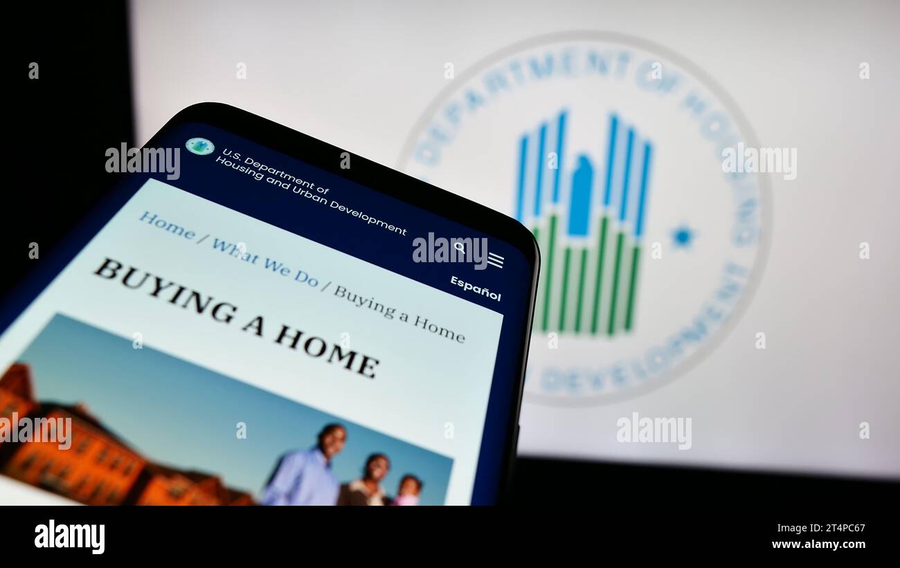 Mobile phone with website of US Department of Housing and Urban Development (HUD) in front of logo. Focus on top-left of phone display. Stock Photo