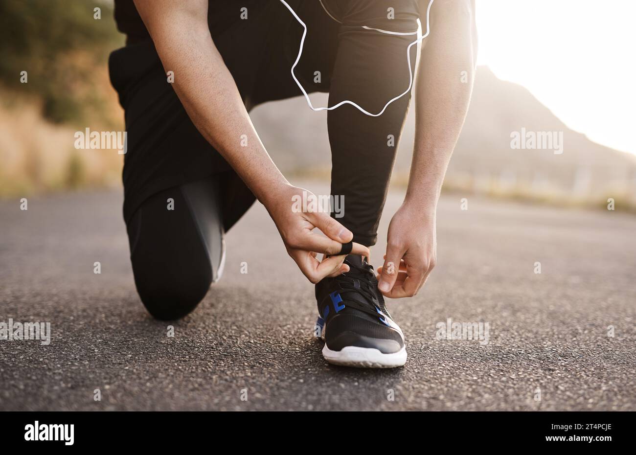 Lacing up to run in the direction of his goals. Closeup shot of an unrecognizable man tying his shoelaces while exercising outdoors. Stock Photo