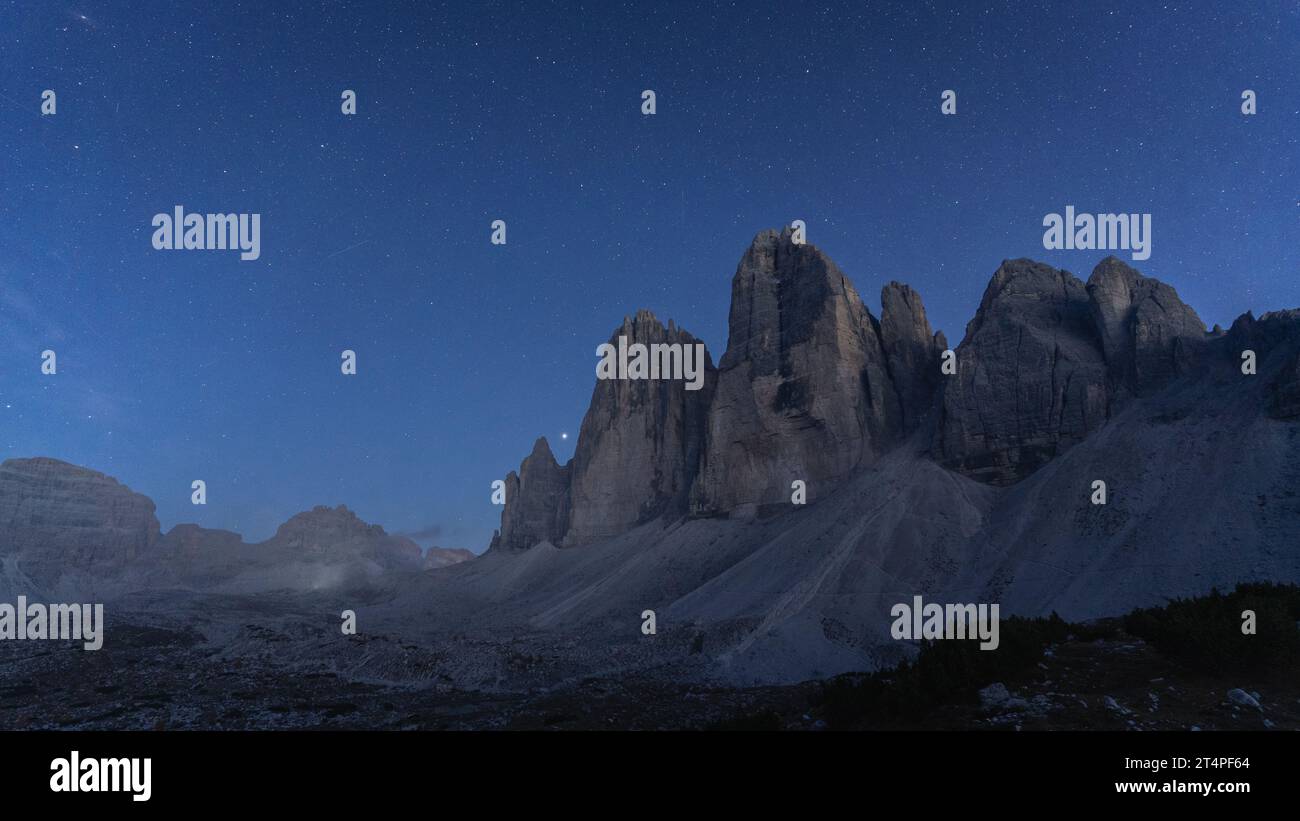 Blue hour and first stars appearing above massive rock mountains Tre Cime, Dolomites, Italy Stock Photo