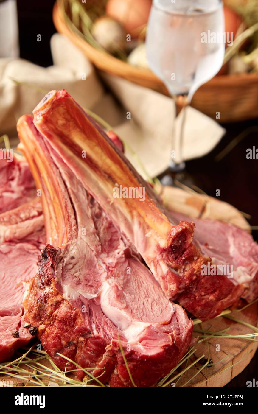 Delicious roasted lamb rack sliced on wooden plate, served with glass of vodka Stock Photo