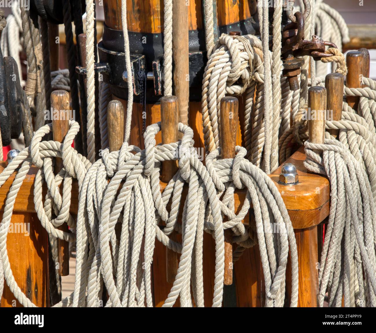 The focus is on the various ropes, knots, and pulleys of a sailing ship Stock Photo
