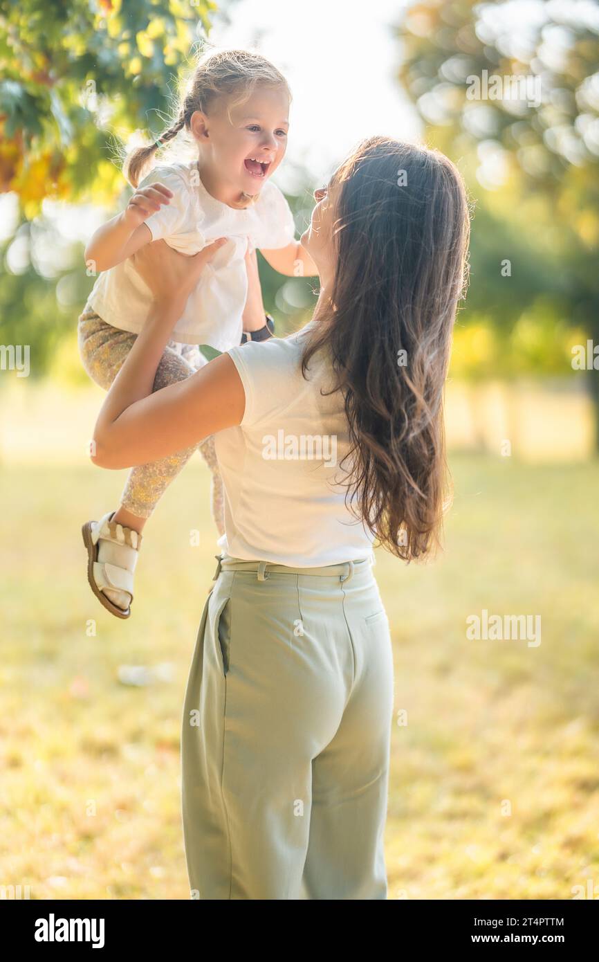Young mother and little daughter having fun together in autumn park in ...