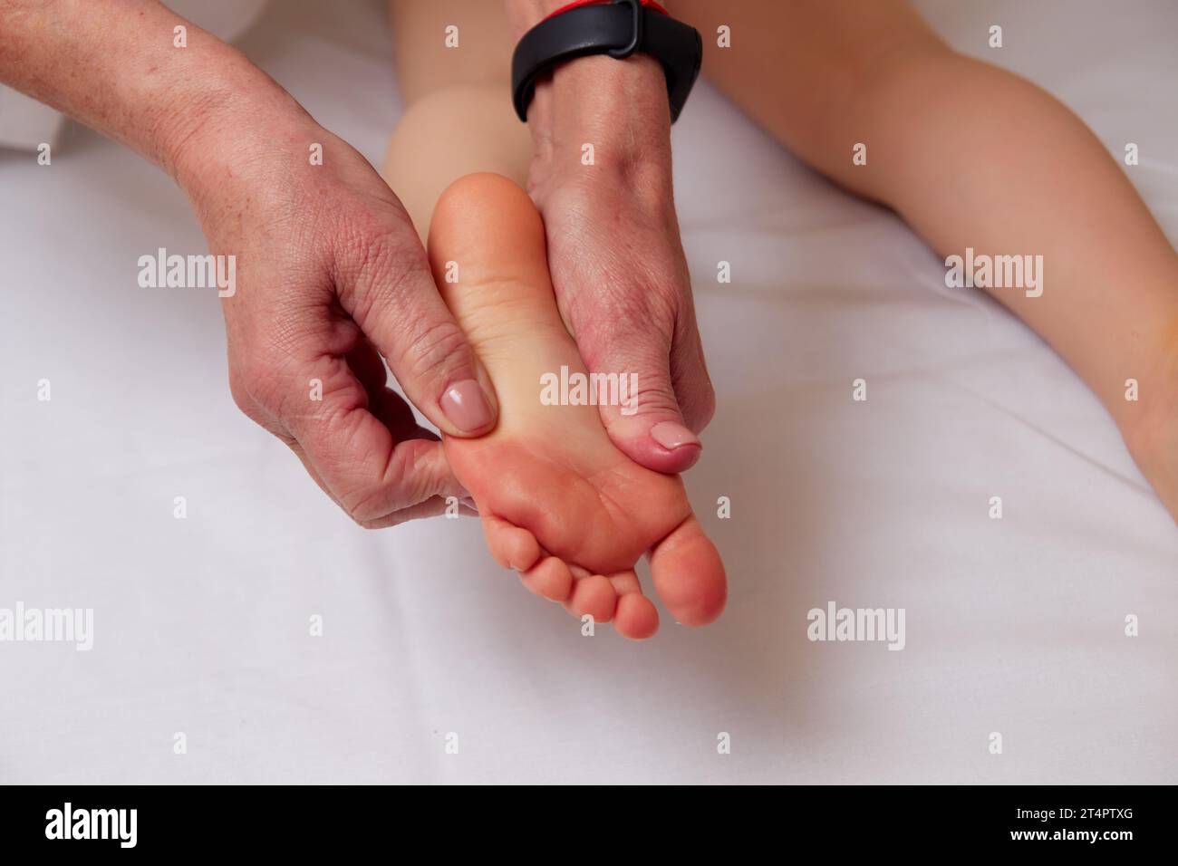 Hands of competent massage therapist massaging foot to child to prevent development of flat feet Stock Photo