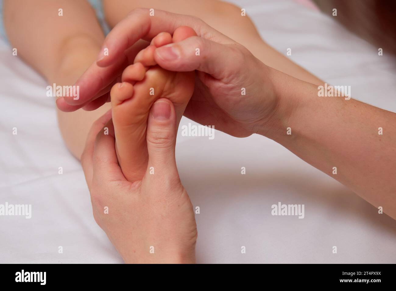Closeup of hands of professional doctor performing pediatric foot massage for improve blood circulation in child body Stock Photo