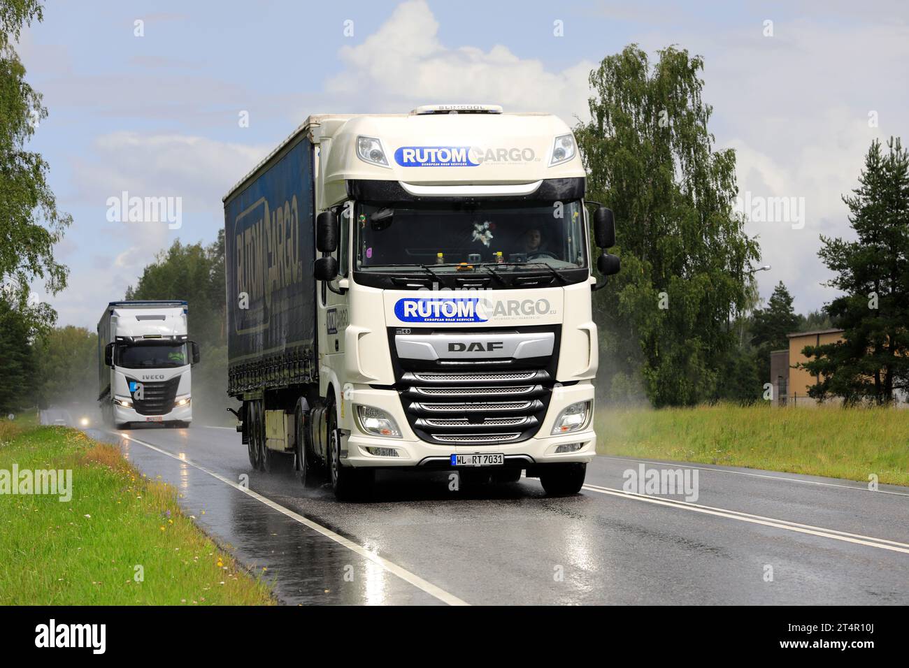 DAF XF Rutom Cargo and Iveco S-Way semi trailer trucks transport goods along highway on a rainy, thundery day. Salo, Finland. July 20, 2023. Stock Photo