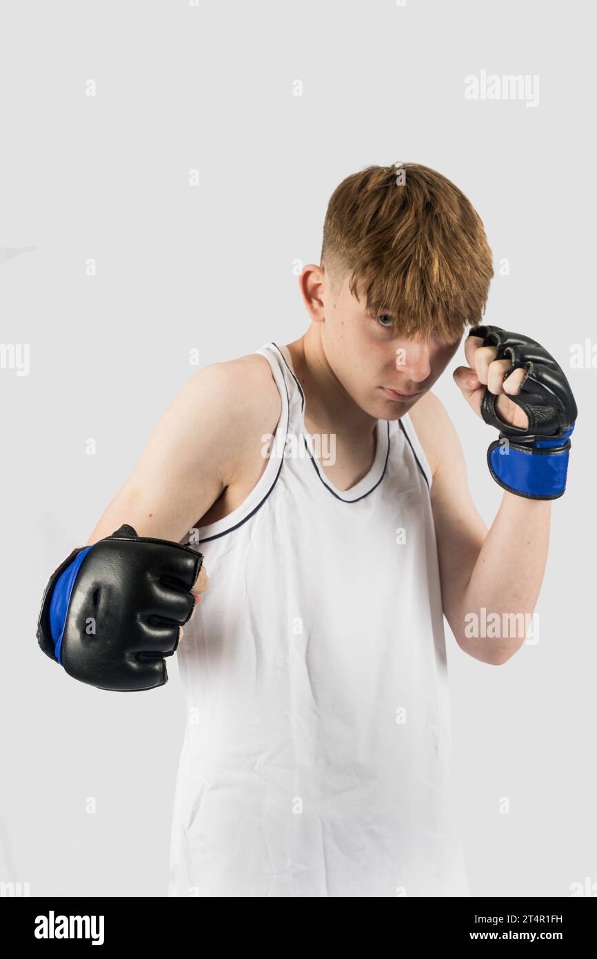 A caucasian teenage boy wearing MMA style boxing gloves punching Stock ...