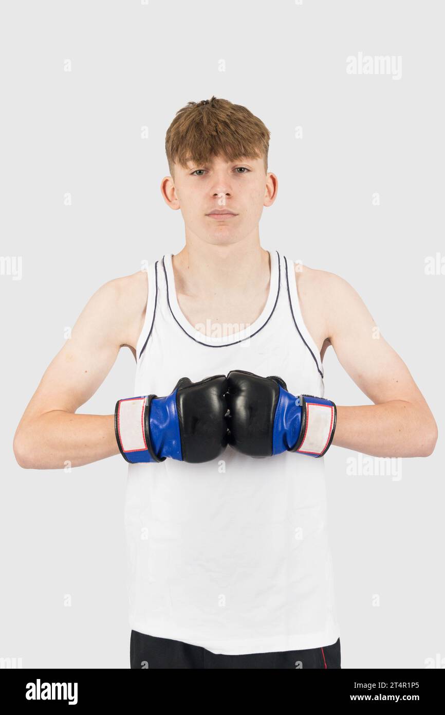 A caucasian teenage boy wearing MMA style boxing gloves posing Stock