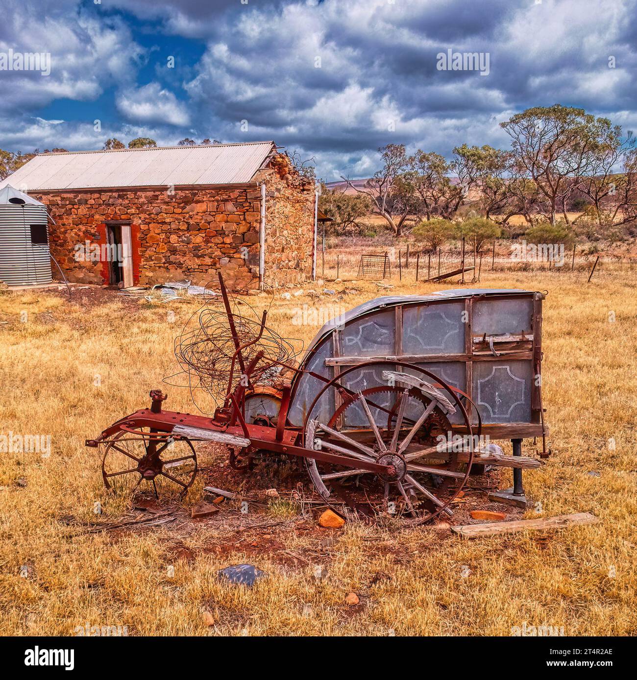 Old stripper harvester in the foreground with an old barn behind Stock Photo