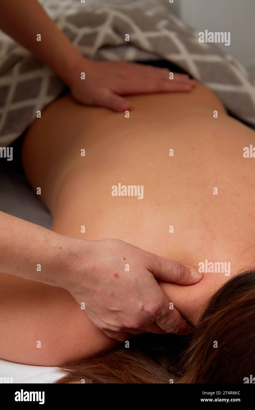 Closeup of skilled masseuse hands giving back pain relief massage to young woman client in medical office Stock Photo