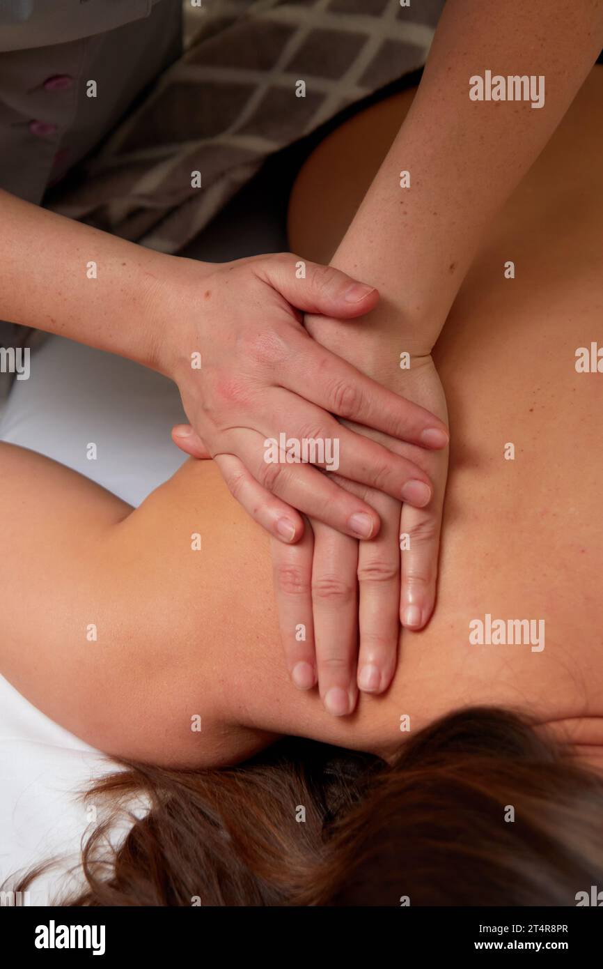Closeup of hands of professional massagist performing back massage to female client in spa center Stock Photo