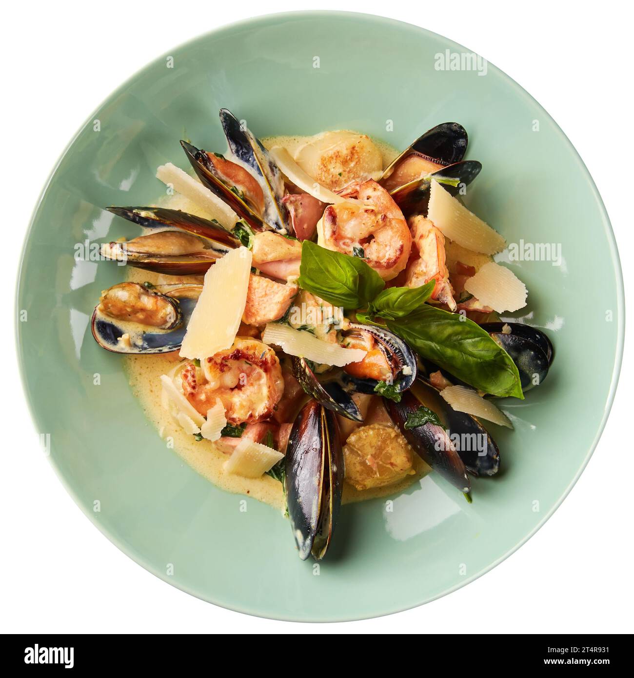 Assorted seafood, mussels, squid, scallops, salmon fillet and tiger shrimps with garlic creamy sauce, parmesan cheese and basil. Isolated on white bac Stock Photo