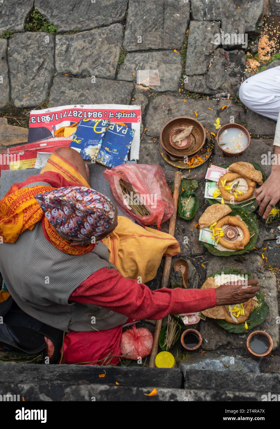 Kathmandu, Nepal: a Brahmin waiting for a family to prepare gifts for the dead along sacred Bagmati river, cremation ceremony at Pashupatinath Temple Stock Photo
