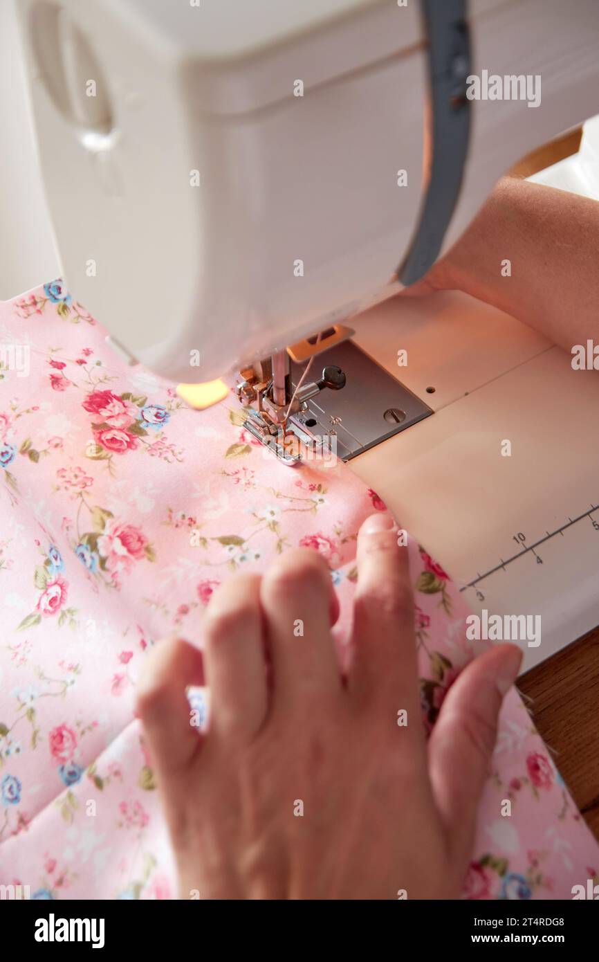 Hands of tailor woman stitching fabric using sewing machine. Stock Photo