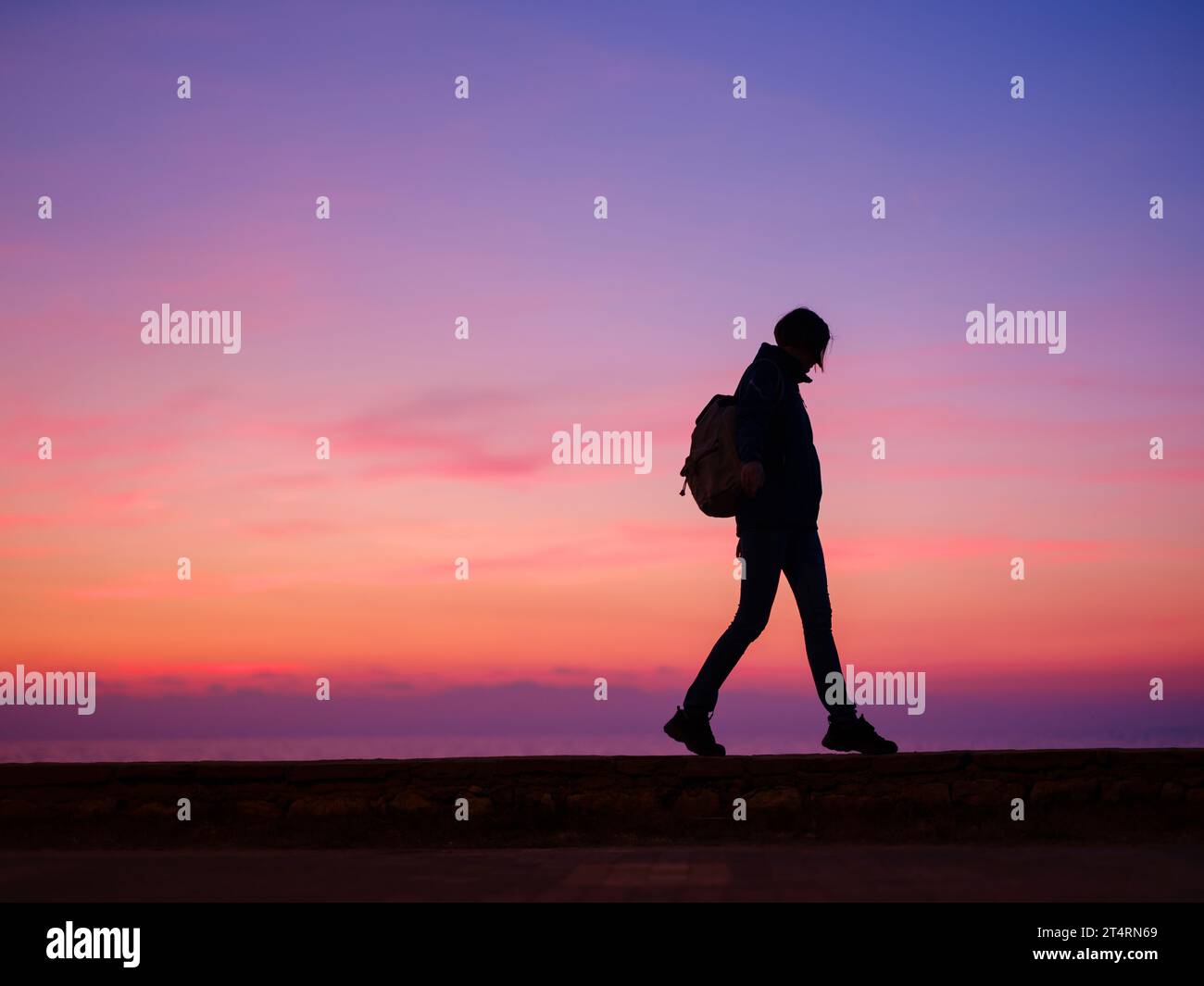 Woman tourist against colorful sunset sky. Travel, tourism concept. Active lifestyle. Stock Photo