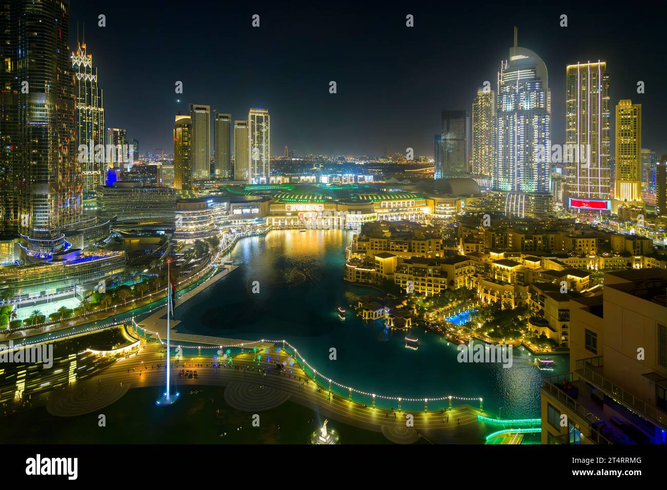The waters of the Dubai Fountain surrounded by illuminated buildings and the Dubai Shopping Mall at night at Downtown Dubai, United Arab Emirates. Stock Photo