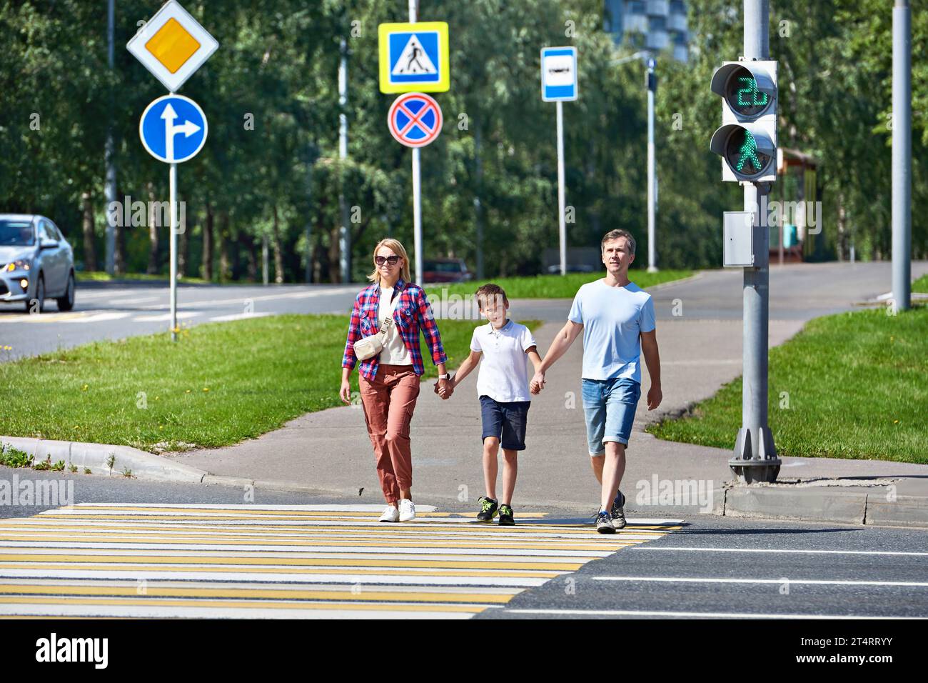 Family, woman, man and child cross the road at a pedestrian crossing ...