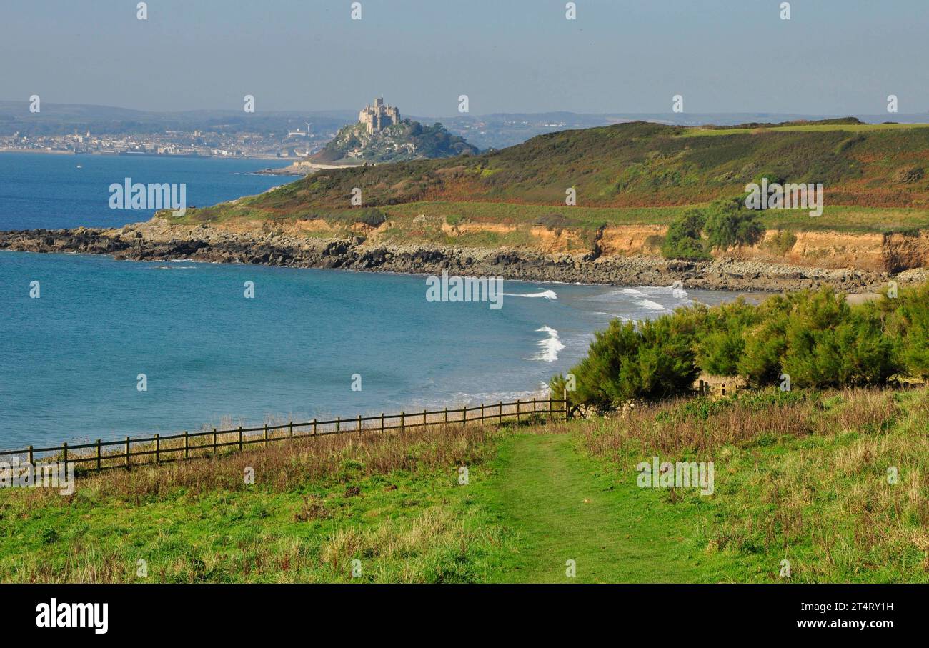 A distant view of St Michaels Mount from the South West Coast path between Perannuthnoe and Marazion as the path follows the winding coastline past ta Stock Photo