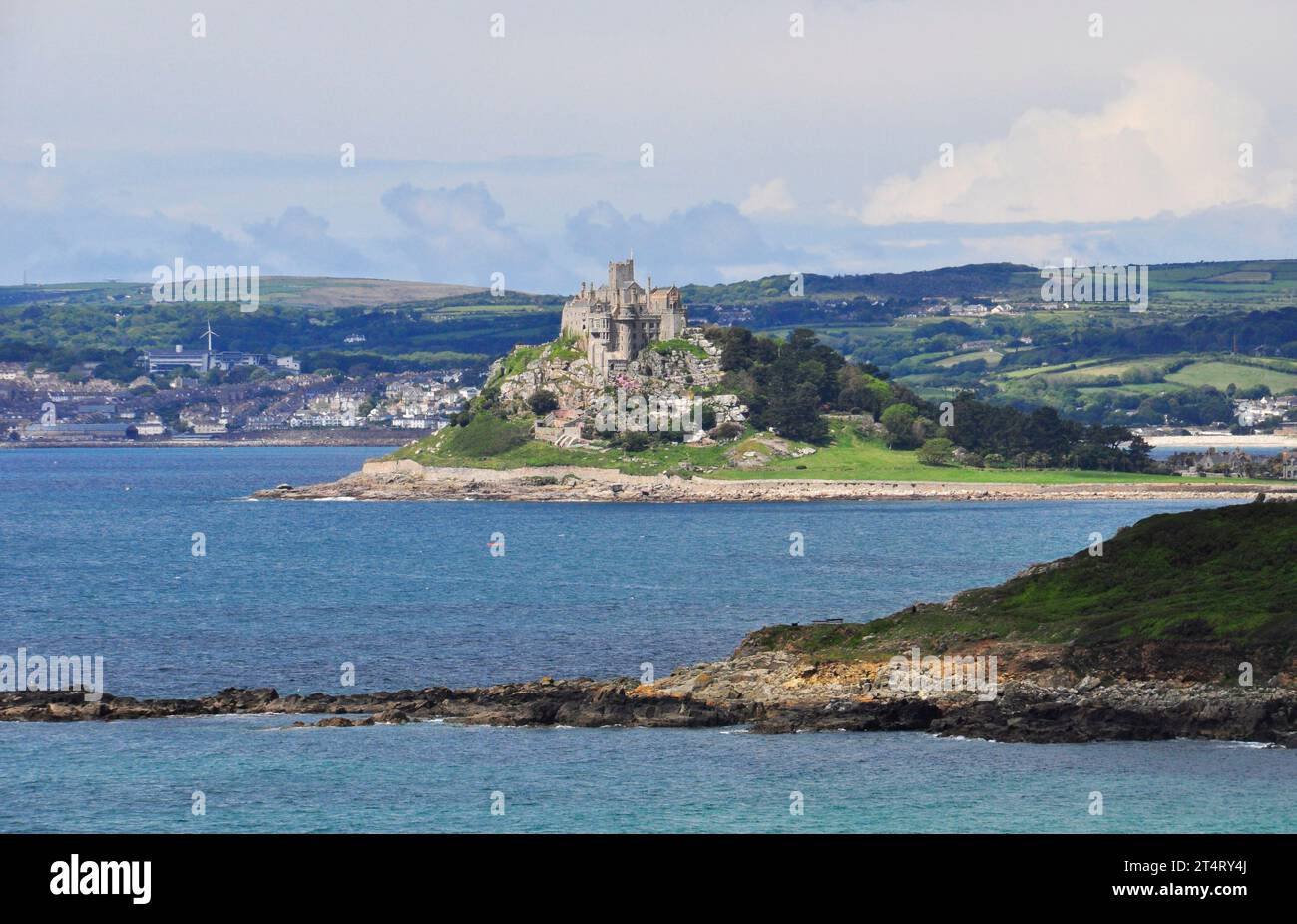 A distant view of St Michaels Mount from the South West Coast path between Perannuthnoe and Marazion as the path follows the winding coastline. Stock Photo