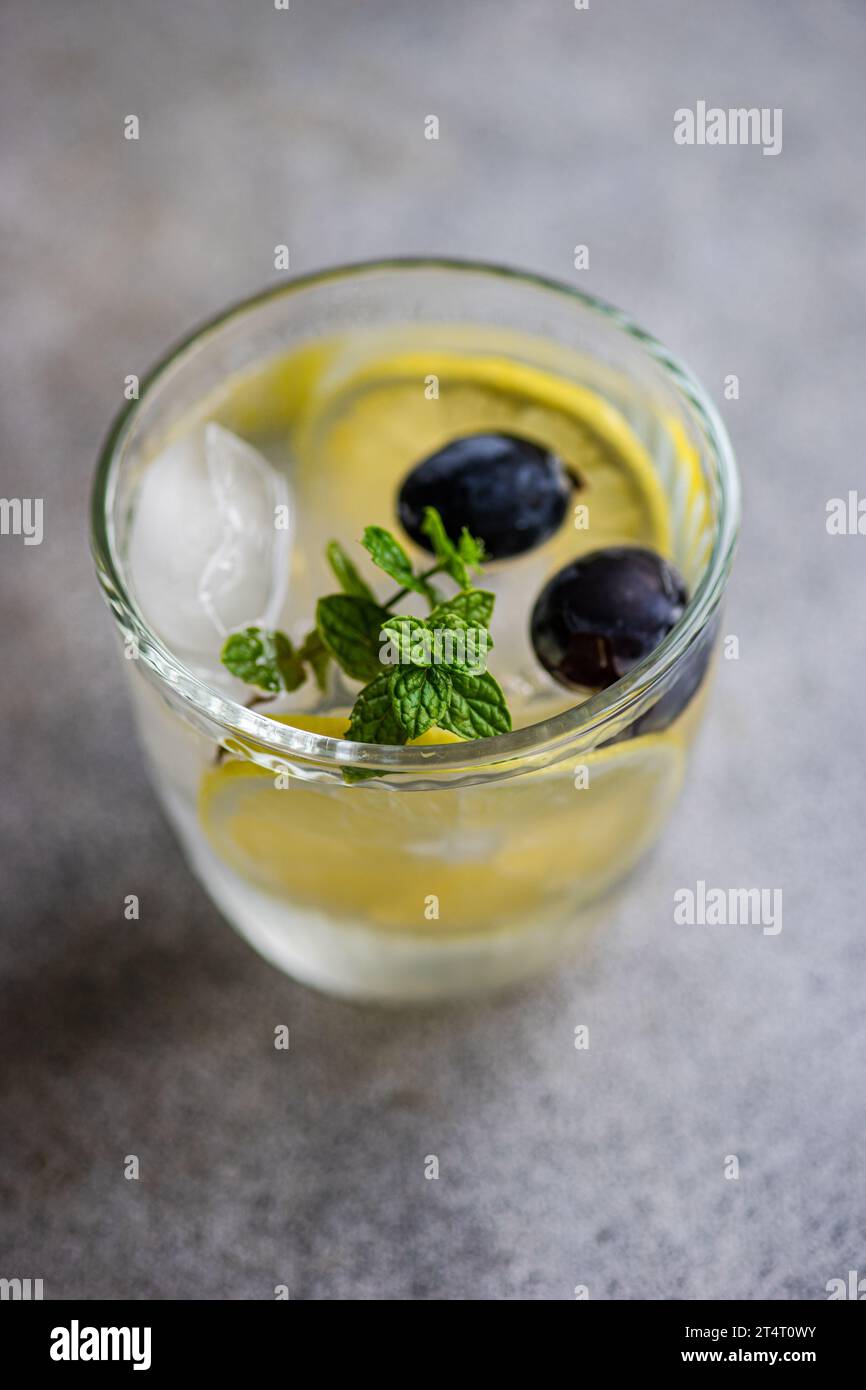 Close-Up of a glass of ice water with fresh lemon, mint and grapes Stock Photo