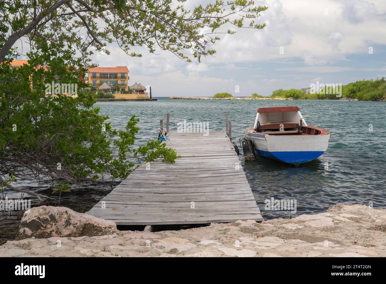 Small, colourful rowing boats, moored alongside a wooden jetty, on the ...