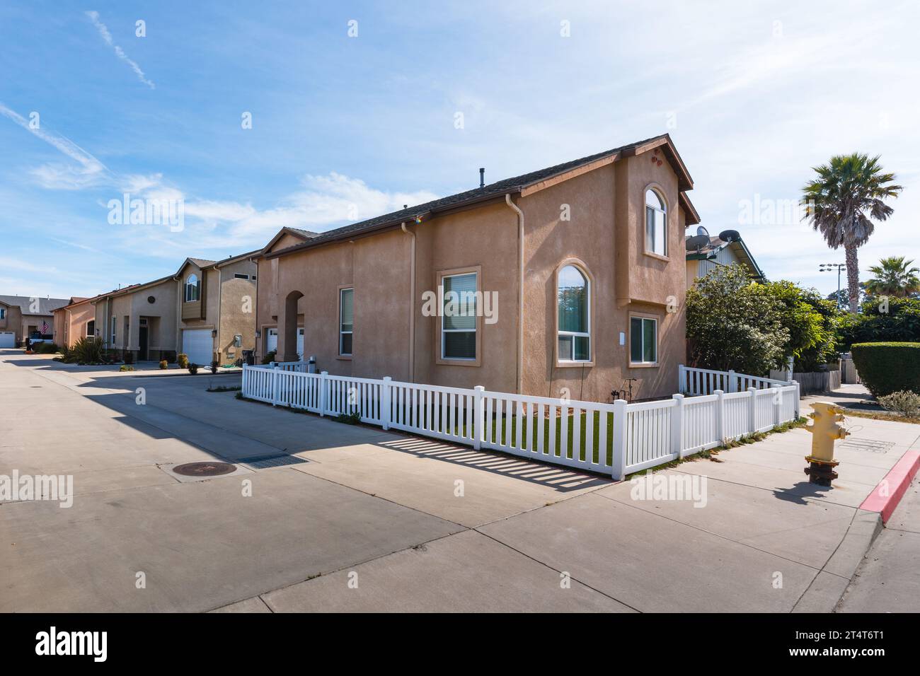 A street view photo of two-story apartment buildings in California, showcasing their charming architecture under the golden sun Stock Photo