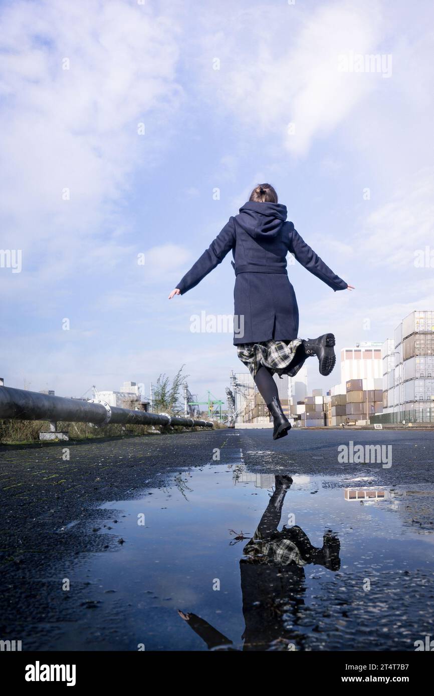 A woman jumps in puddles on the street on a rainy day Stock Photo