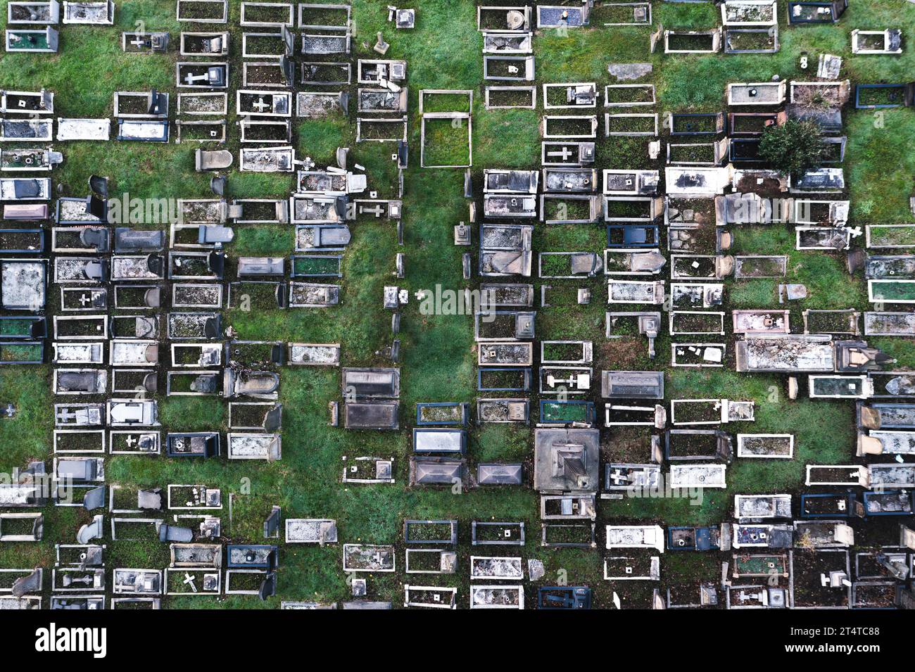 Aerial view directly above a packed inner city cemetery with rows of graves and tombstones in a grief or bereavement concept with copy space Stock Photo