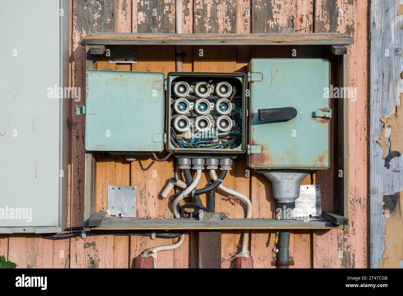 Old open fuse box on weathered wooden wall Stock Photo