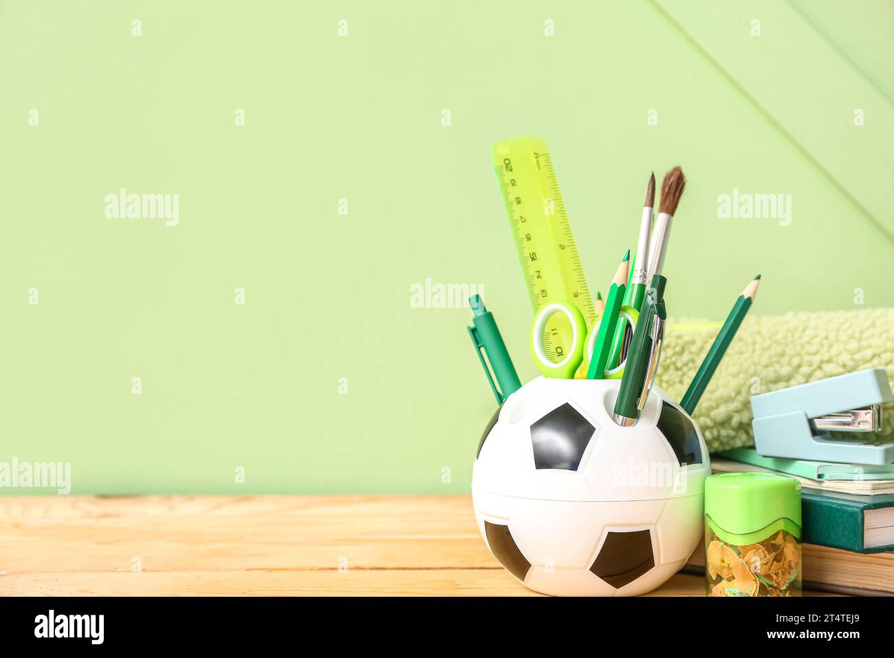 Holder in shape of soccer ball with different stationery on wooden desk, closeup Stock Photo