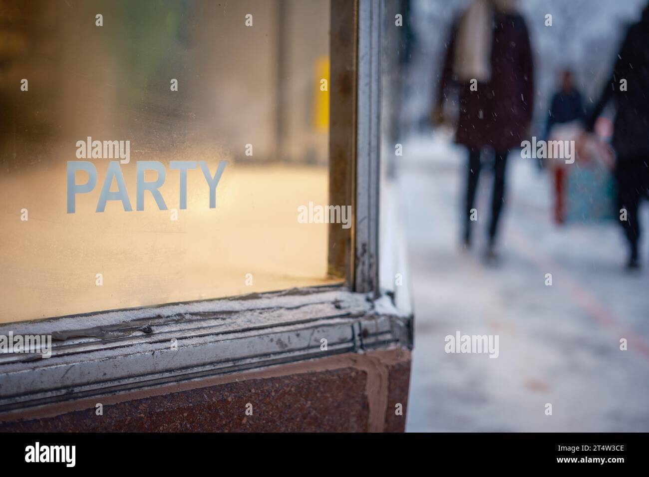 Storefront window with the word 'Party' on a winter day with people walking by. Stock Photo