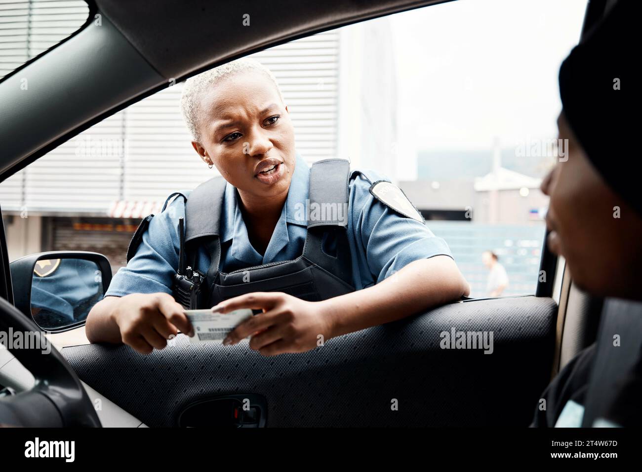 Talking, drivers license or police officer in city to check info for law enforcement, protection or street safety. Black woman, traffic stop or cop on Stock Photo