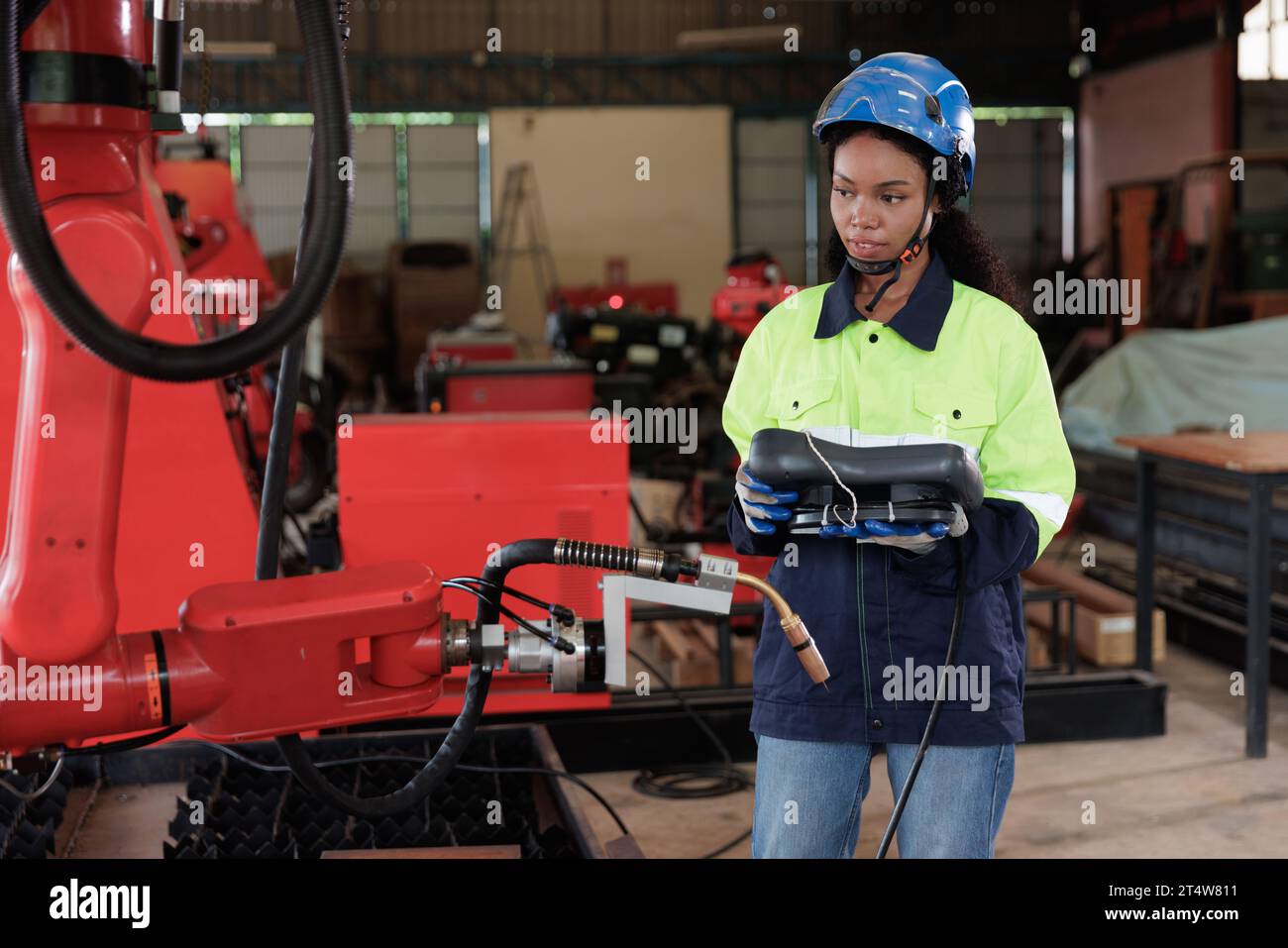 Woman engineer controlling and checking robot arm at factory