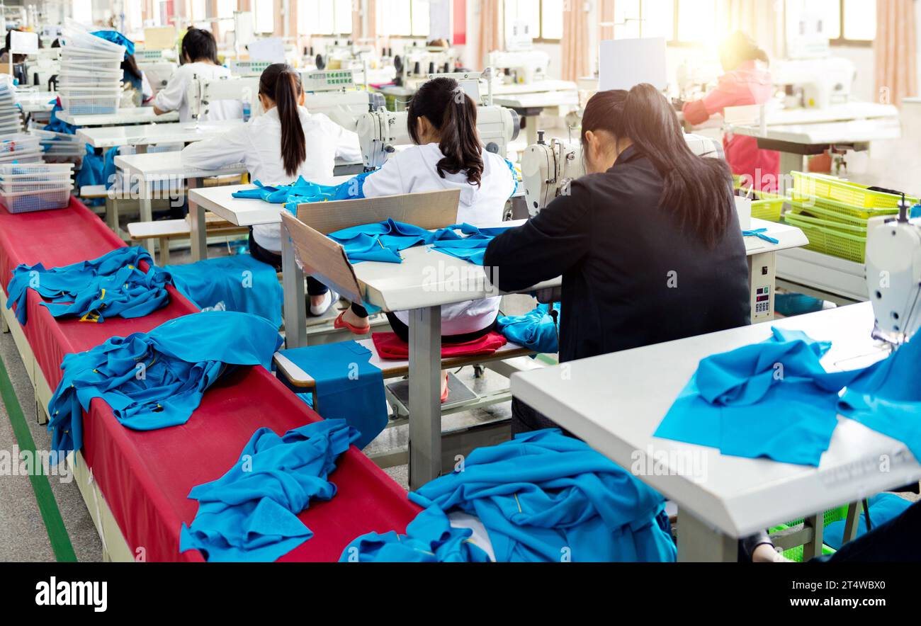 Rear view of chinese female blue collar workers working in clothing factory in a row Stock Photo