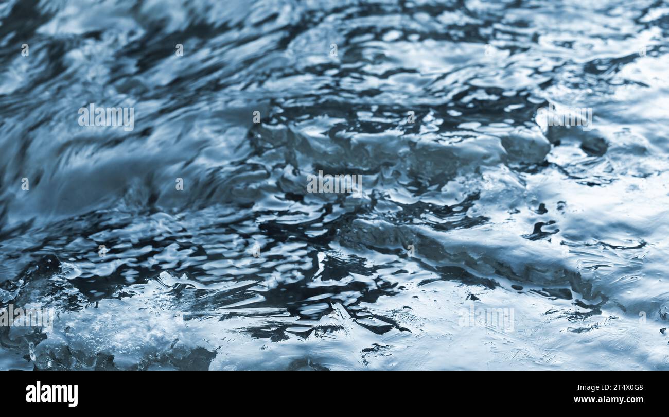 Ice crystal structures are in a flowing stream water, close-up natural background photo Stock Photo