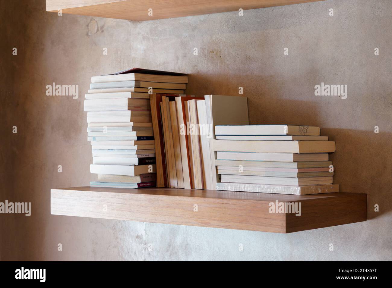 Stack of books on floating wooden bookshelf. Education and knowledge concept. Pile of books to read. House interior decoration Stock Photo