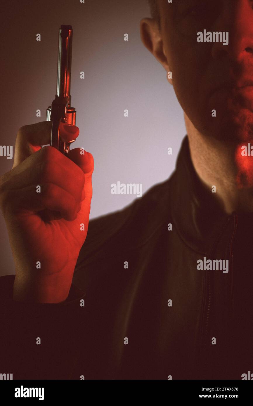 Gunman killer holding pistol artistic photo book cover design with colors and lighting. Stock Photo