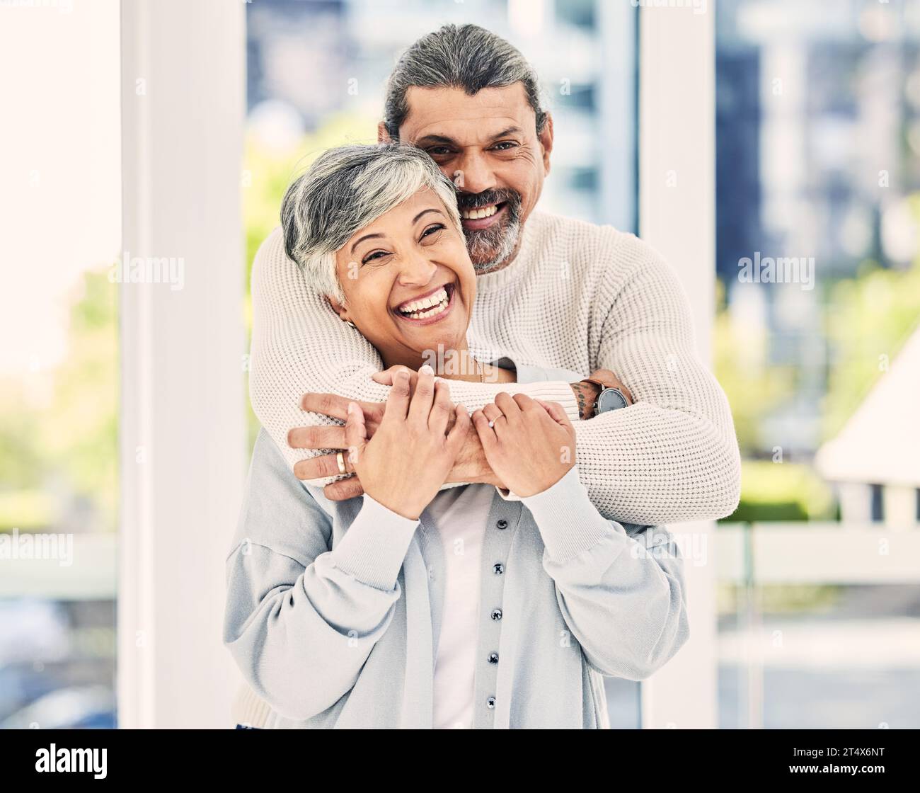 Funny, portrait and elderly couple hug in home, laugh and relax in retirement together. Face, embrace and senior man and woman smile for love, care Stock Photo
