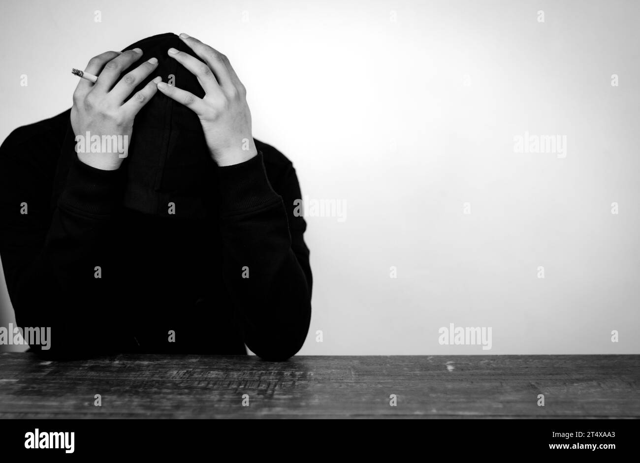 Portrait of Depressed Man wearing black hoodie hiding his face with hands. Stressed, Hopeless, Frustration, Mental disorder and Broken heart. Stock Photo
