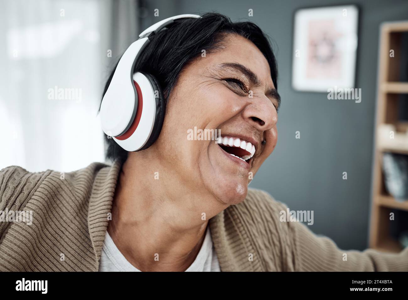 Headphones, face or happy woman streaming music or dancing to relax with freedom at home. Retirement, smile or excited senior person laughing or Stock Photo